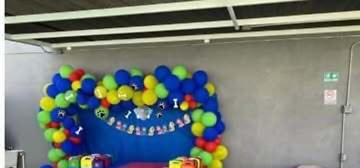 Mesa de pastel con arco de globos bajo el área techada